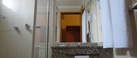 A bathroom with a shower, a sink with a mirror, and a towel rack.