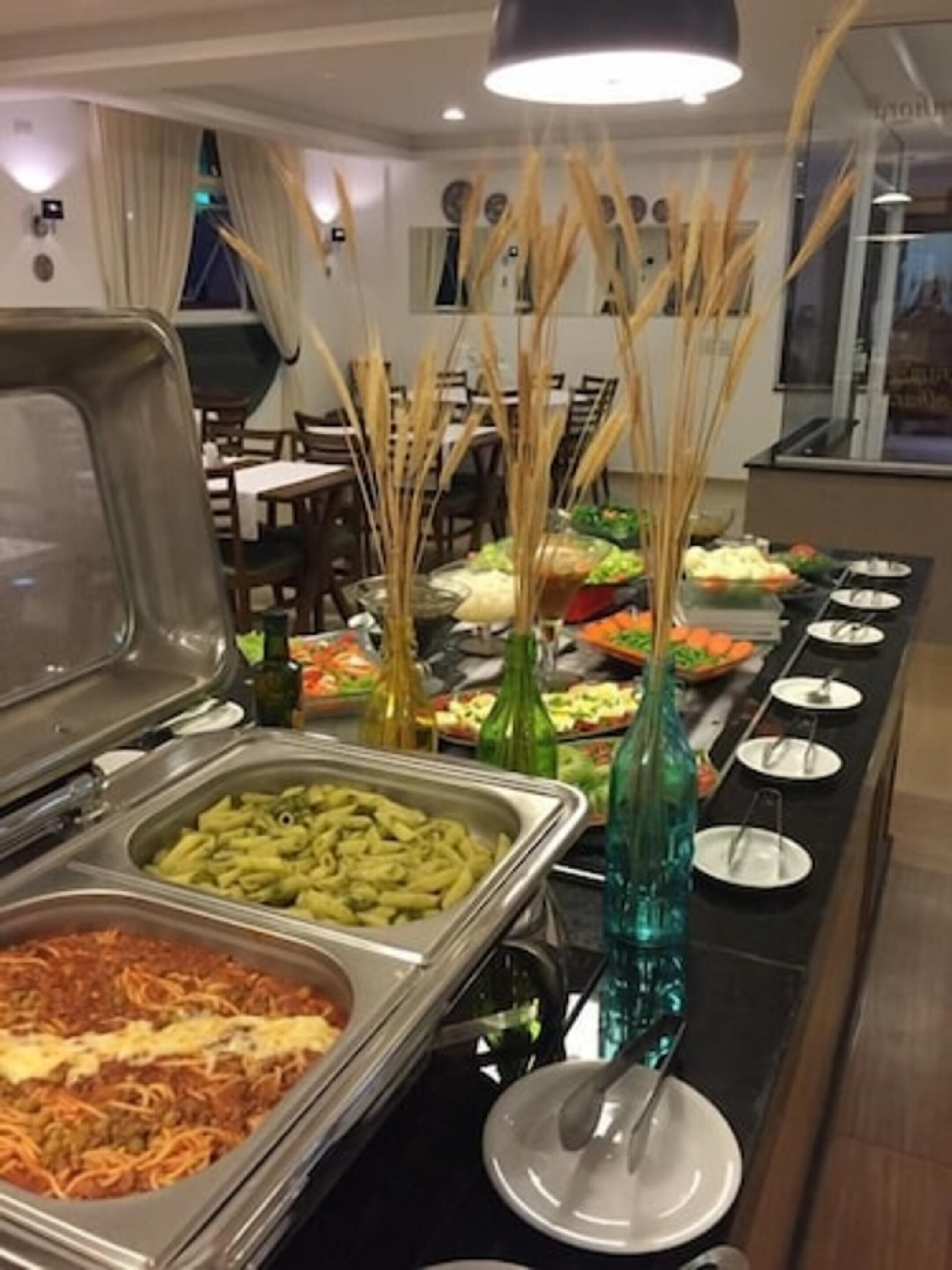 Una mesa de buffet con diversos alimentos y un florero decorativo.