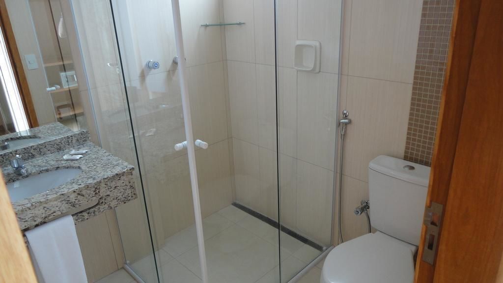 Ein Badezimmer mit Duschkabine aus Glas, Toilette und Waschbecken auf einer Granitplatte.
