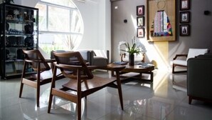 A modern living room with a glass cabinet, a round window, and a wall decorated with framed pictures.