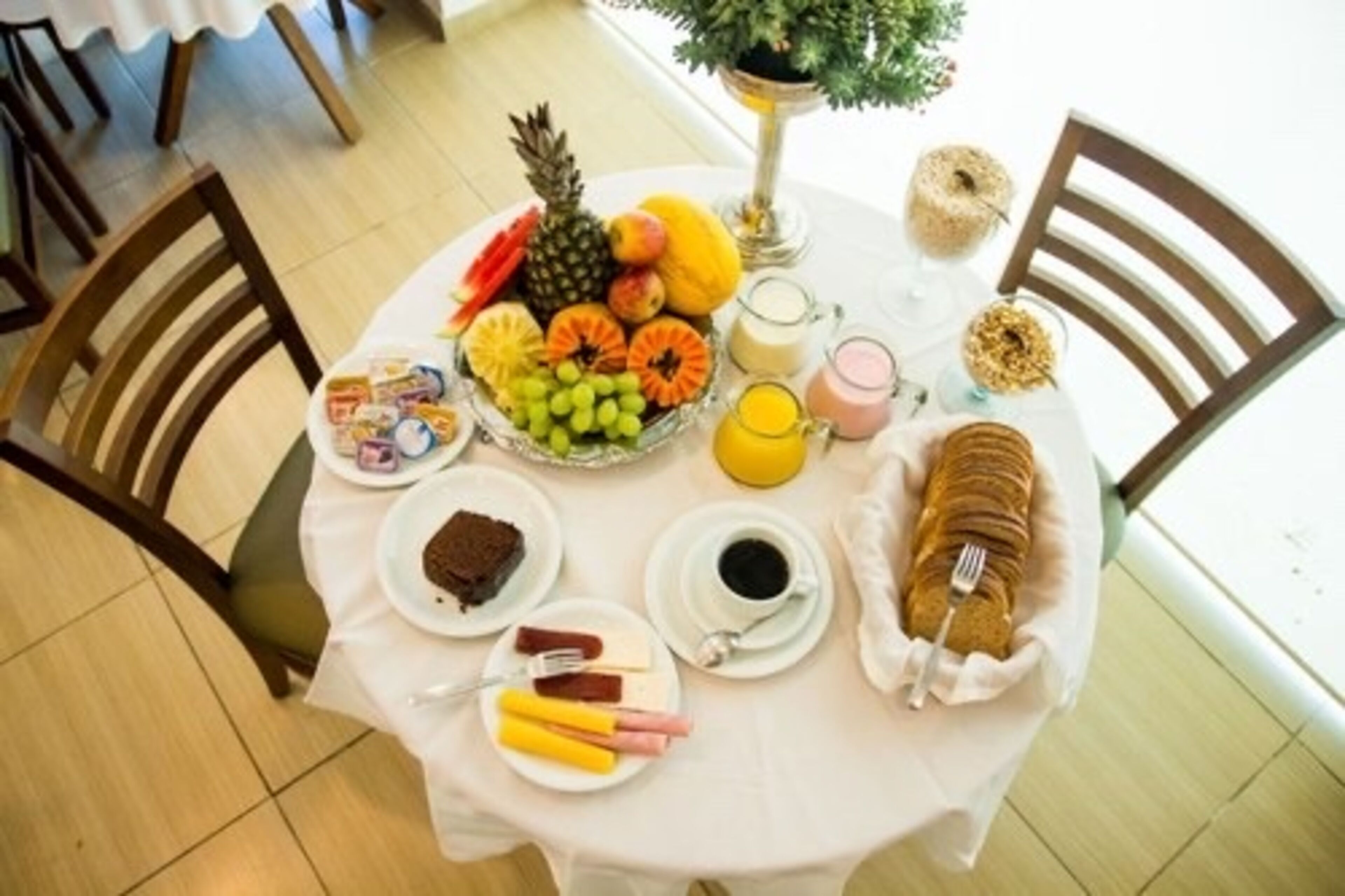 Une table de petit-déjeuner avec un assortiment de fruits, de viennoiseries et de boissons.