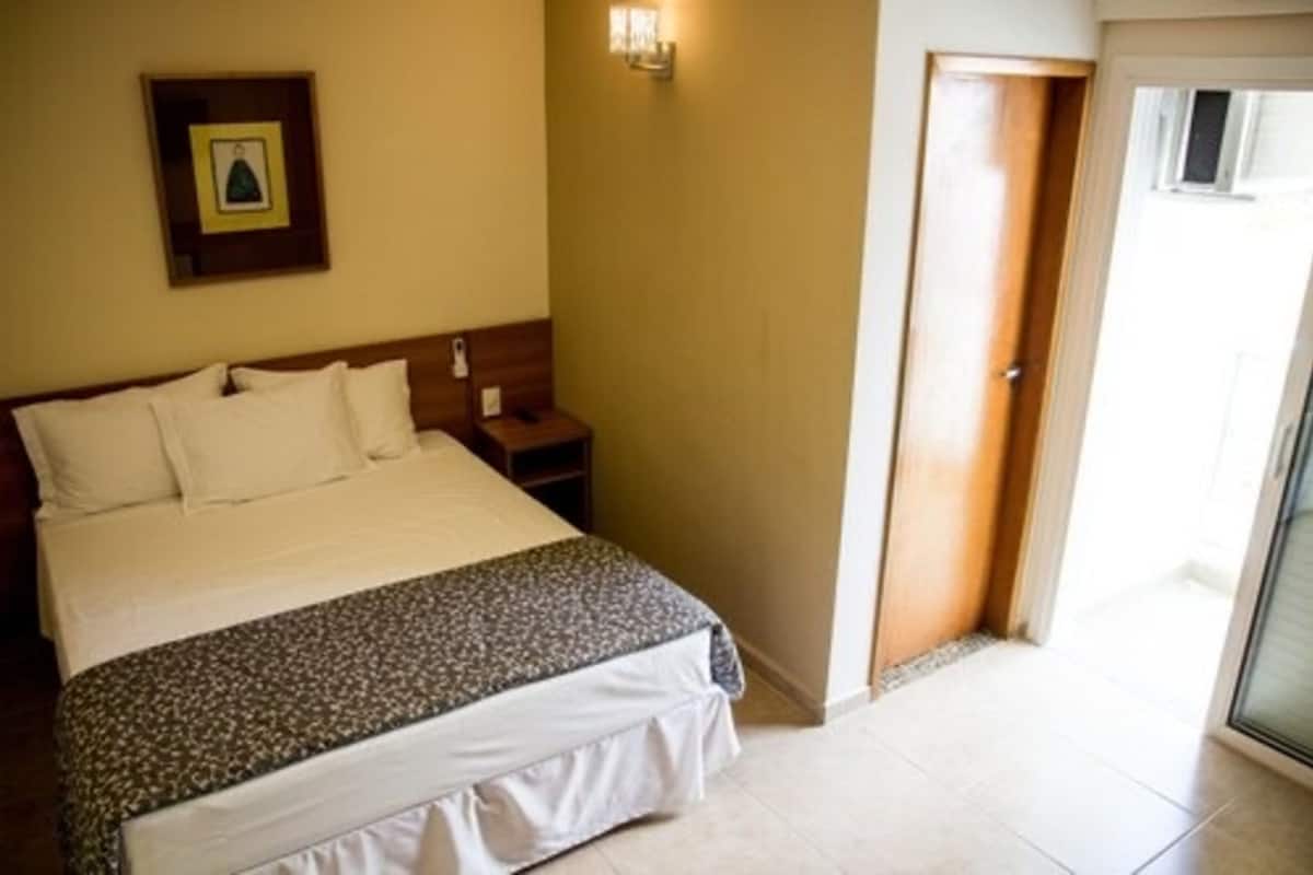 Une chambre à coucher avec un lit, une table de chevet et une porte donnant sur un balcon.