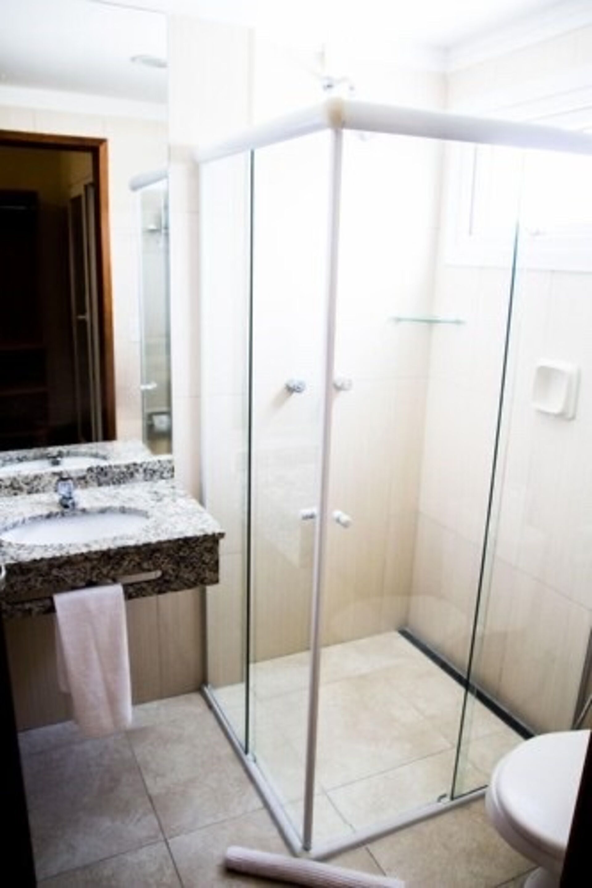 A modern bathroom with a glass shower enclosure, a granite countertop sink, and a toilet.