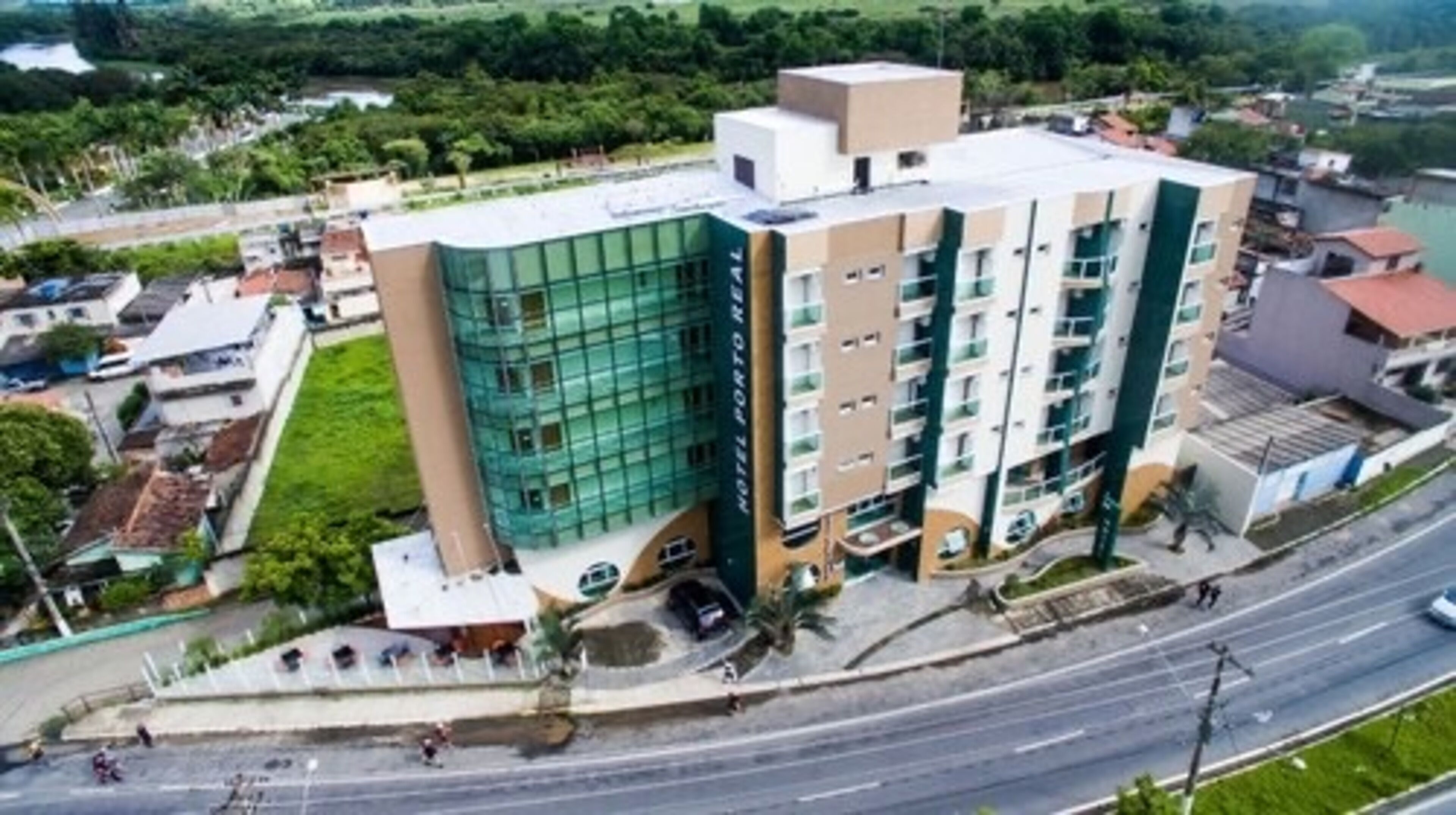 A multi-story hotel with a modern glass facade, a central courtyard, and a parking area.