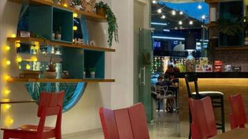 A restaurant interior with wooden shelves, red chairs, and a bar area.