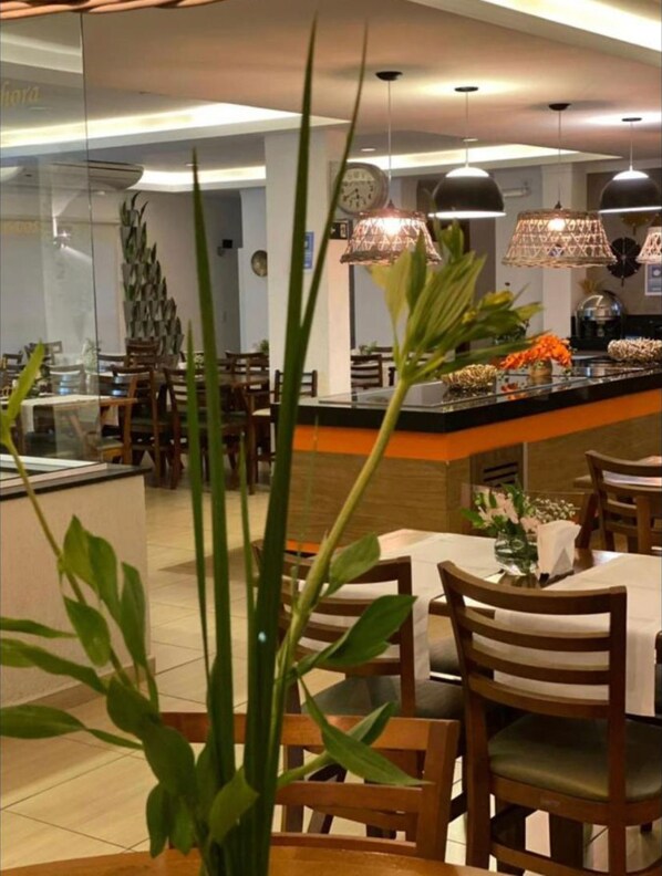 A modern restaurant interior with wooden furniture, hanging pendant lights, and a central island with a buffet.