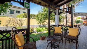 Een terras buiten met rieten meubilair en een pergola.
