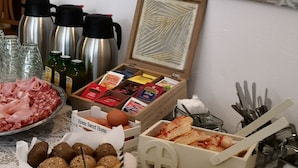 Diverse etenswaren, zoals brood, kaas en eieren, op een tafel met een kantkleed.