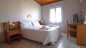 Een keurig opgemaakt slaapkamer met een bed, nachtkastjes, een bureau en een stoel.