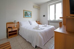 A hotel room with a bed, bedside tables, a desk, a chair, a television, a window, and a painting on the wall. - Hotel Villa Giada (Massa)