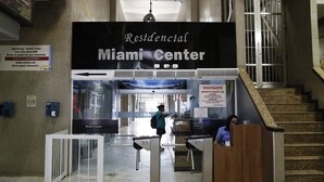 Ein Empfangsbereich mit einem Schild für das Miami Center, einer Treppe und einem Empfangstresen, hinter dem sich eine Person befindet.