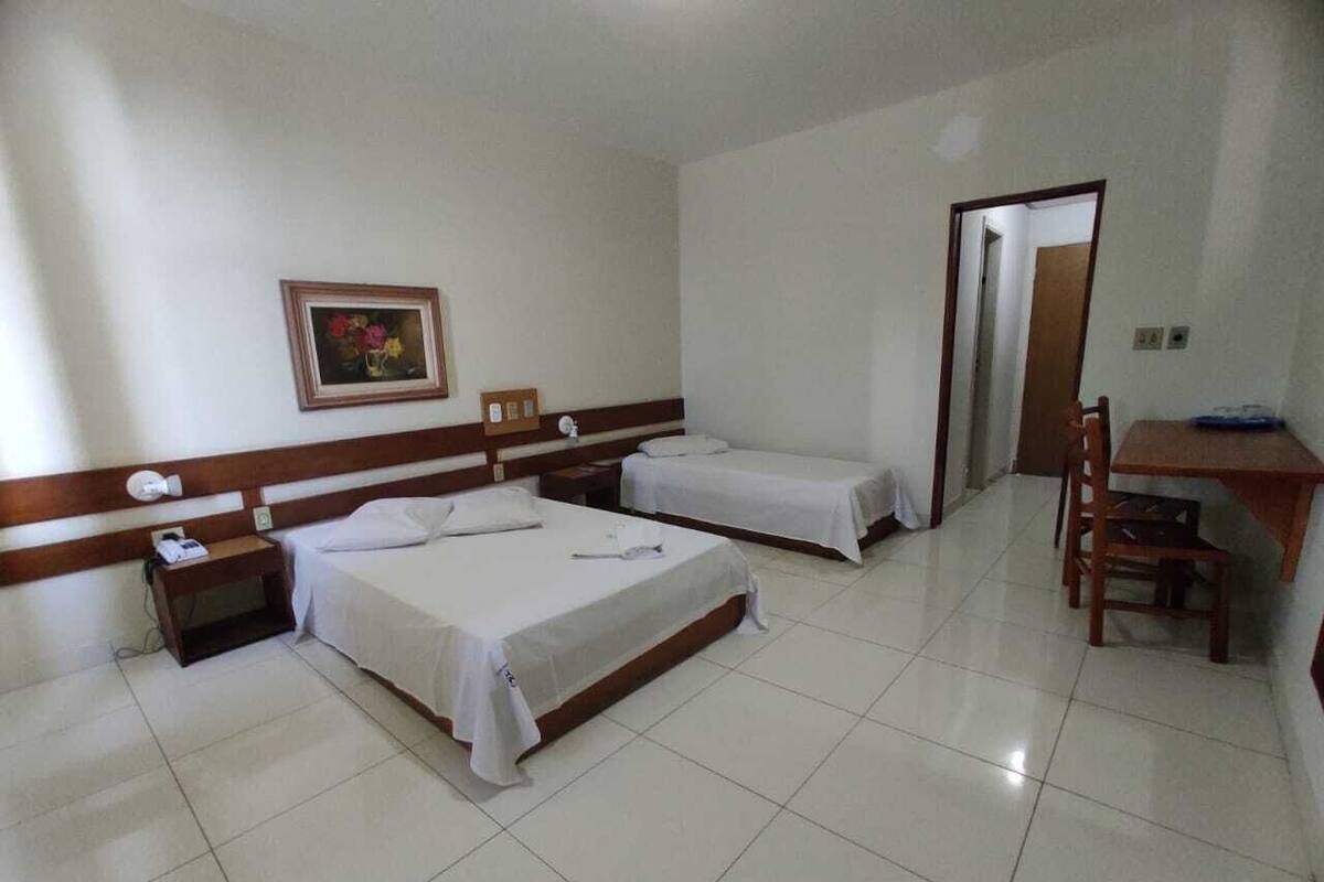 A hotel room with two beds, a desk, and a chair.