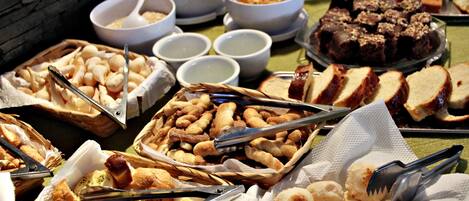 A buffet table with various food items including bread, pastries, and desserts.