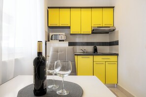 A kitchen with yellow cabinets, a white countertop, and a wine bottle with glasses on a placemat.