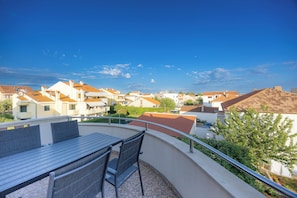 Ein Balkon mit Tisch und Stühlen, mit Blick auf eine Wohngegend mit Häusern.