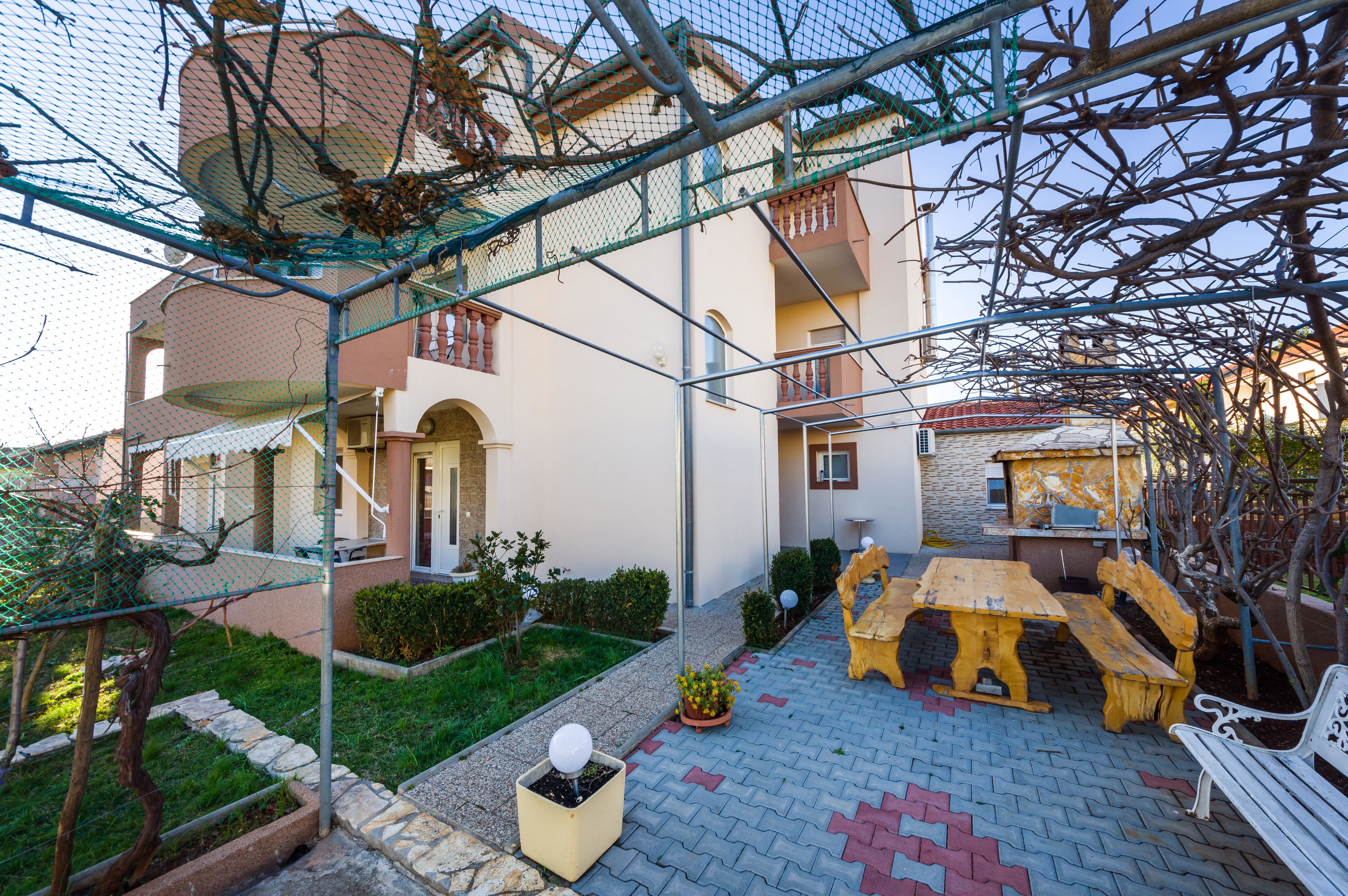 A courtyard with a wooden bench, a white bench, and a small table.