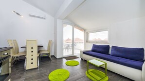 Una sala de estar moderna con sofá, sillas, una mesa de comedor y una zona de cocina.