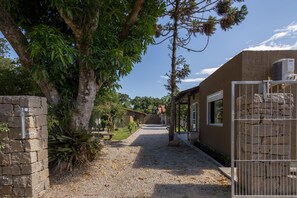 A pathway leading to a building with stone walls and a metal gate. - Cabanas Canasvieiras (Florianópolis)