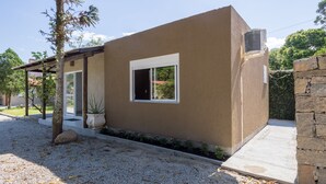 Een modern huis met een beige gevel, een klein raam en een stenen muur.