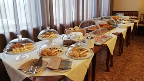 Ein Buffet mit verschiedenen Speisen, darunter Gebäck und Desserts, unter Glassdecken.