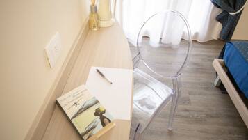 A clear plastic chair, a wooden desk, a book, and a pen.