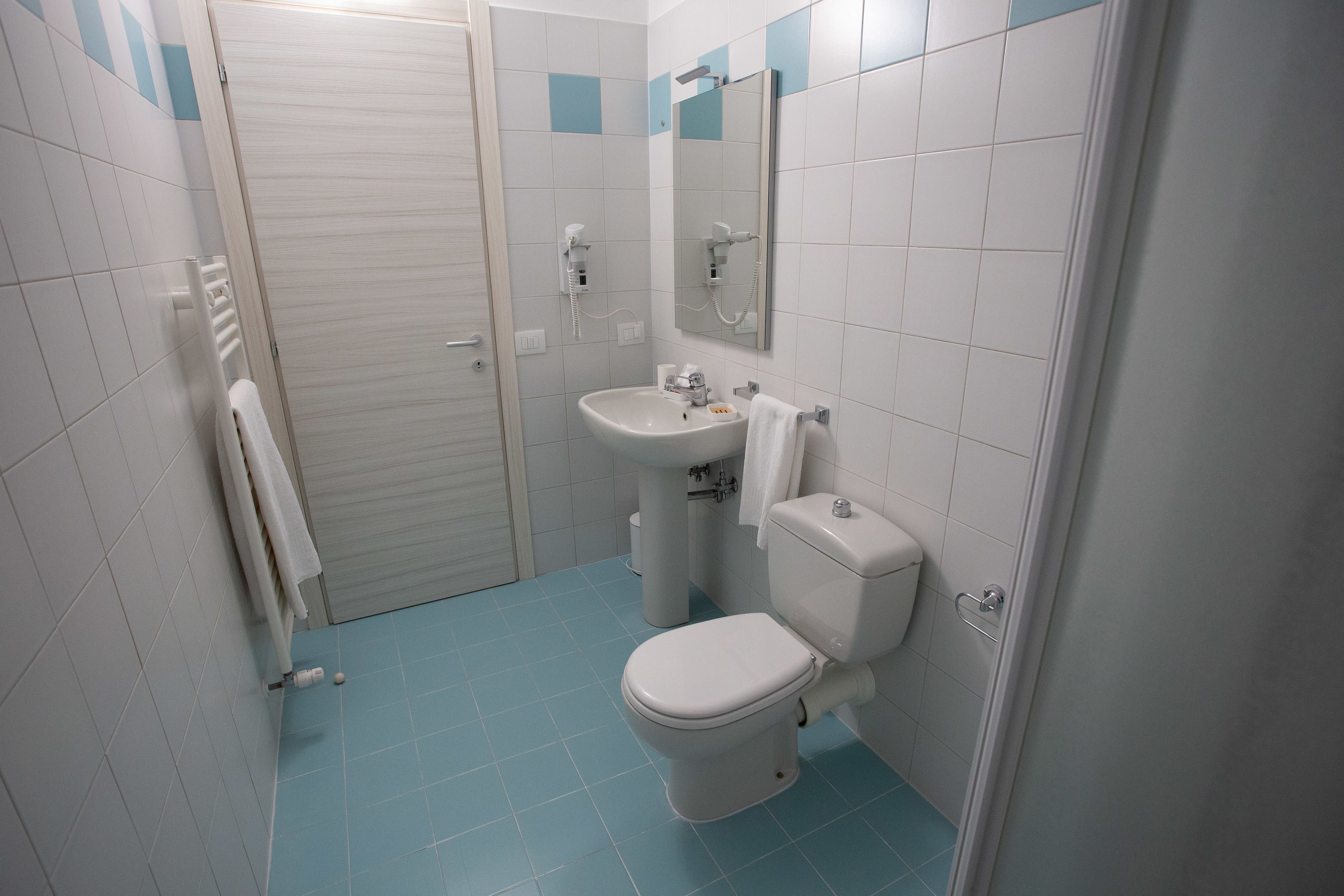 Un baño con inodoro, lavamanos y espejo.