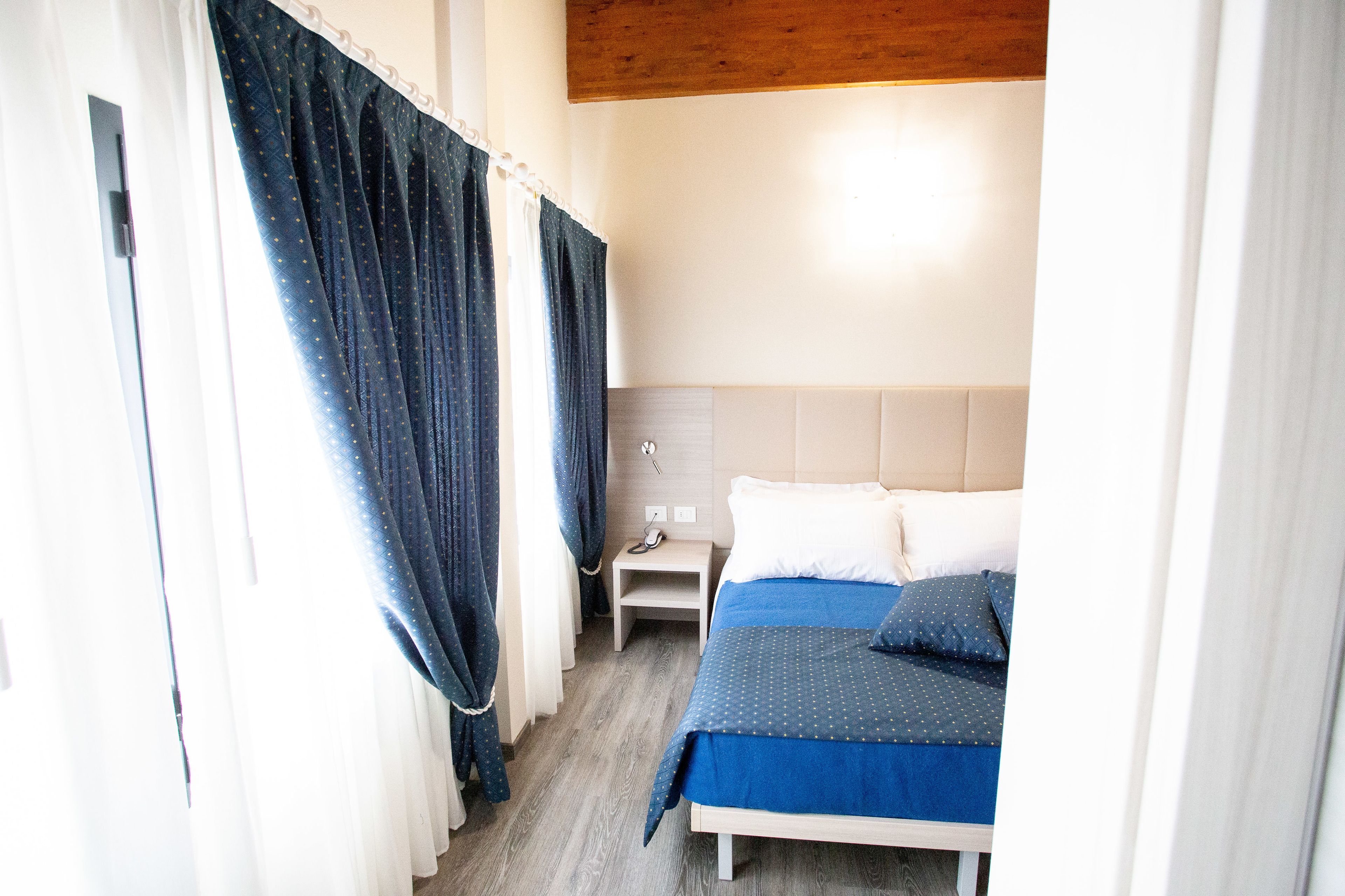 Une chambre à coucher avec un lit, une table de chevet et des rideaux.
