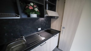 Eine kleine Küche mit schwarzer Arbeitsplatte, einem Spülbecken und einem Schrank.