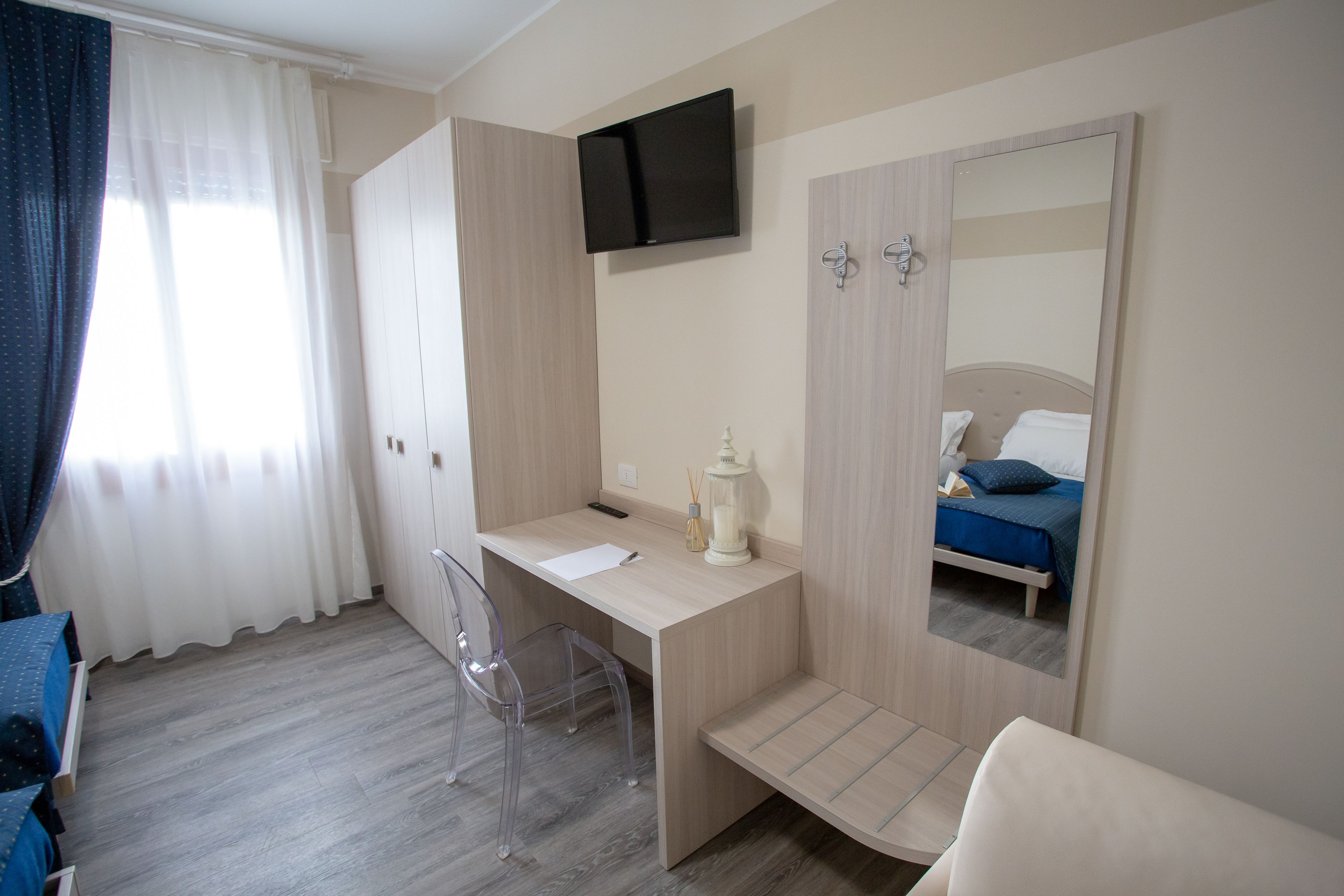 A bedroom with a bed, a desk, a chair, a TV, and a wardrobe.