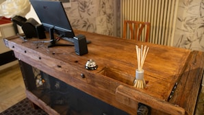 Ein hölzerner Empfangstresen mit einem Computer, einer Registrierkasse und einem dekorativen Flaschenhalter.