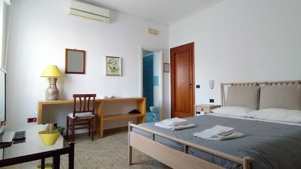 A bedroom with a bed, bedside tables, a desk with a chair, a lamp, and a mirror. - B&B Vanvitelli (Caserta)