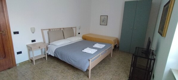 A bedroom with a bed, bedside table, and a wardrobe.