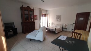 A bedroom with a bed, bedside table, lamp, and a wooden cabinet with books. - B&B Vanvitelli (Caserta)