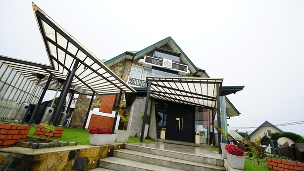 A modern house with a unique architectural design, featuring a large glass entrance and a well-maintained garden. - Horton Towers & Cottages (Nuwara Eliya)