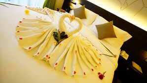 A neatly made bed with a swan-shaped towel arrangement and scattered flowers. - Horton Towers & Cottages (Nuwara Eliya)
