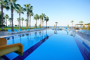 A pool area with lounge chairs and umbrellas, surrounded by palm trees and a view of the ocean. - Perre Delta Hotel (Alanya)