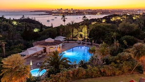 A pool area with a view of the city skyline at sunset. - Hotel Casabela (Lagoa)