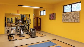 Un gimnasio con equipo de ejercicio, colchonetas y un espejo.