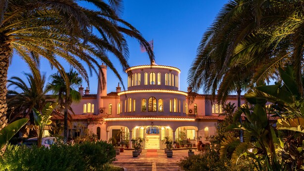 A large, circular building with a central courtyard, surrounded by palm trees and lush greenery. - Hotel Casabela (Lagoa)