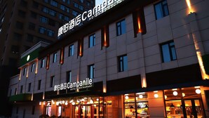 Hotelli, jossa on moderni julkisivu, valaistut kyltit ja kutsuva sisäänkäynti sekä ulkona oleva oleskelualue.