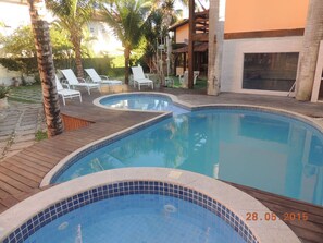 Una piscina al aire libre, sillones reclinables de piscina