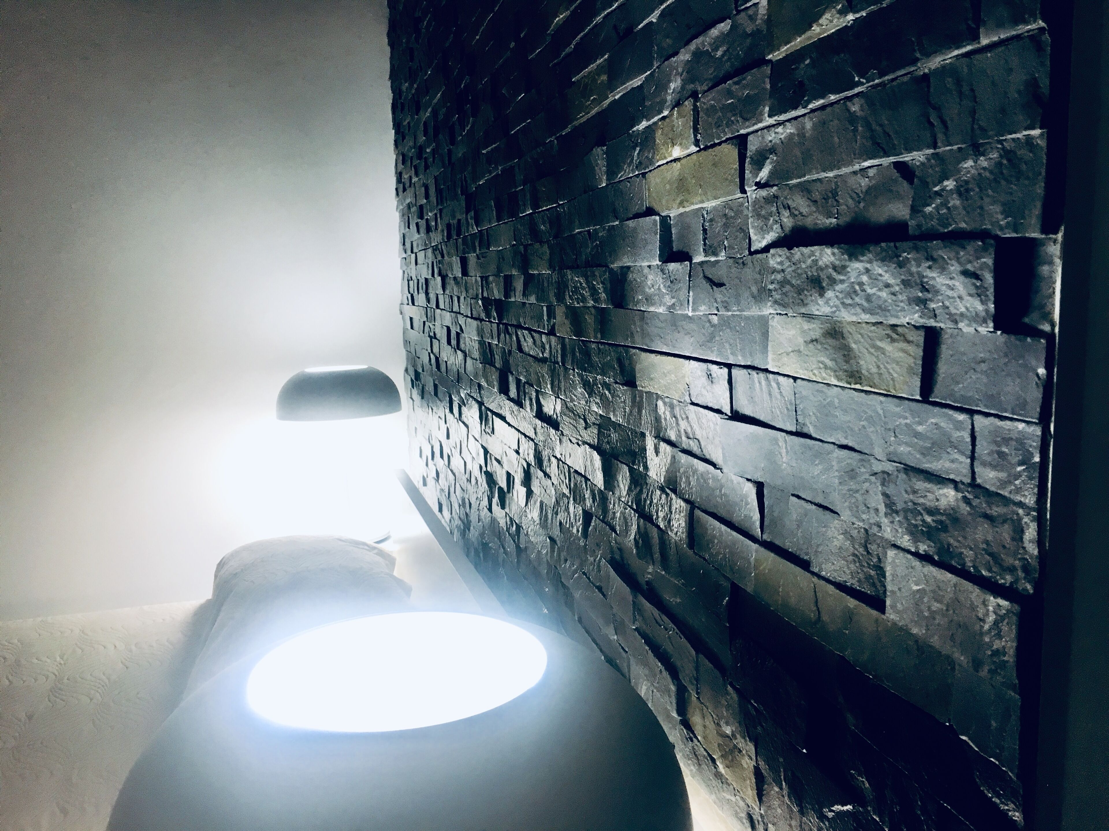 Un baño con pared de piedra y un inodoro.