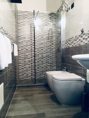 A modern bathroom with a glass shower enclosure, a toilet, and a sink. - Franz Guest House (Naples)