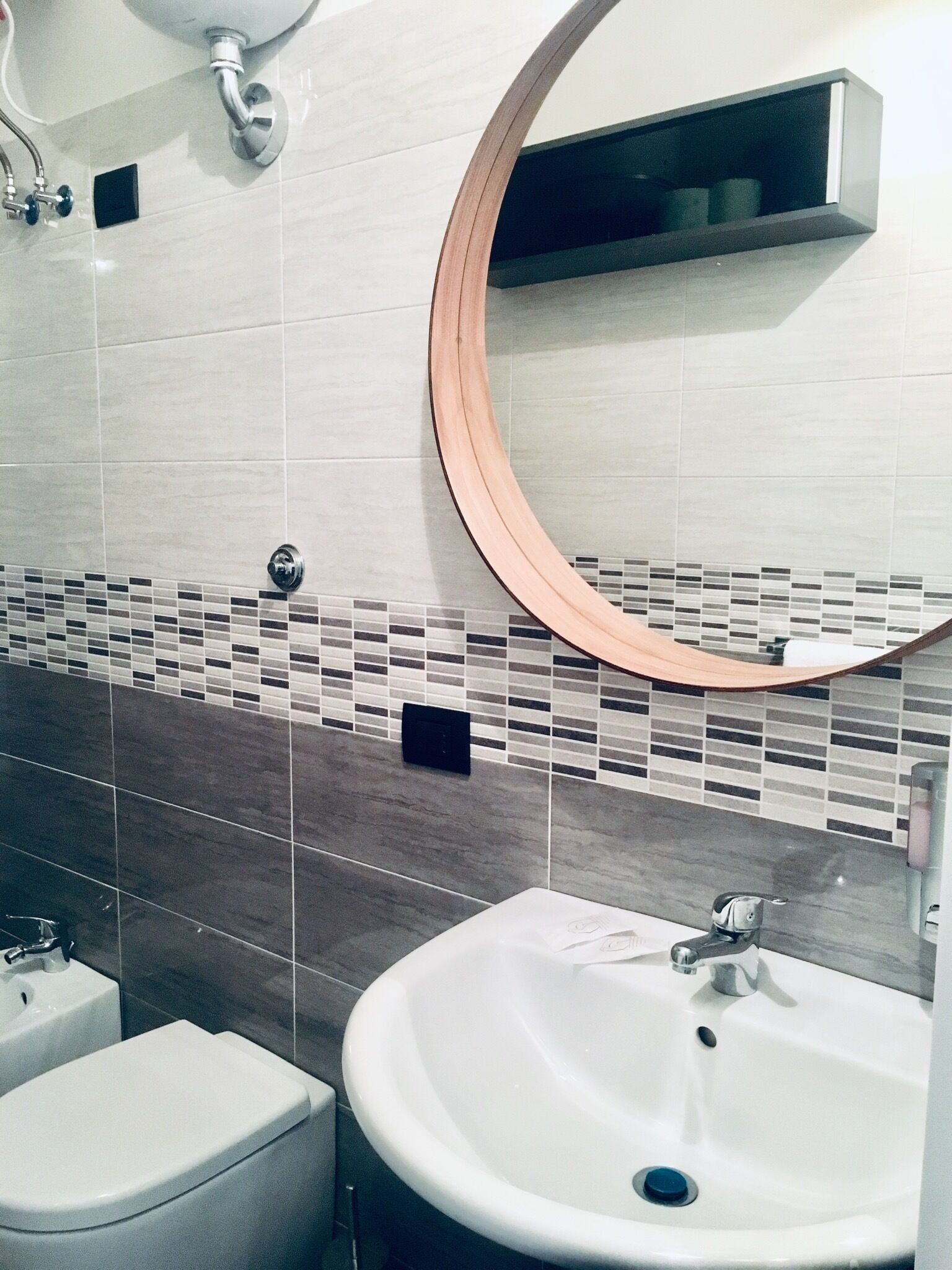 A bathroom with a white sink, a toilet, and a mirror with a wooden frame.