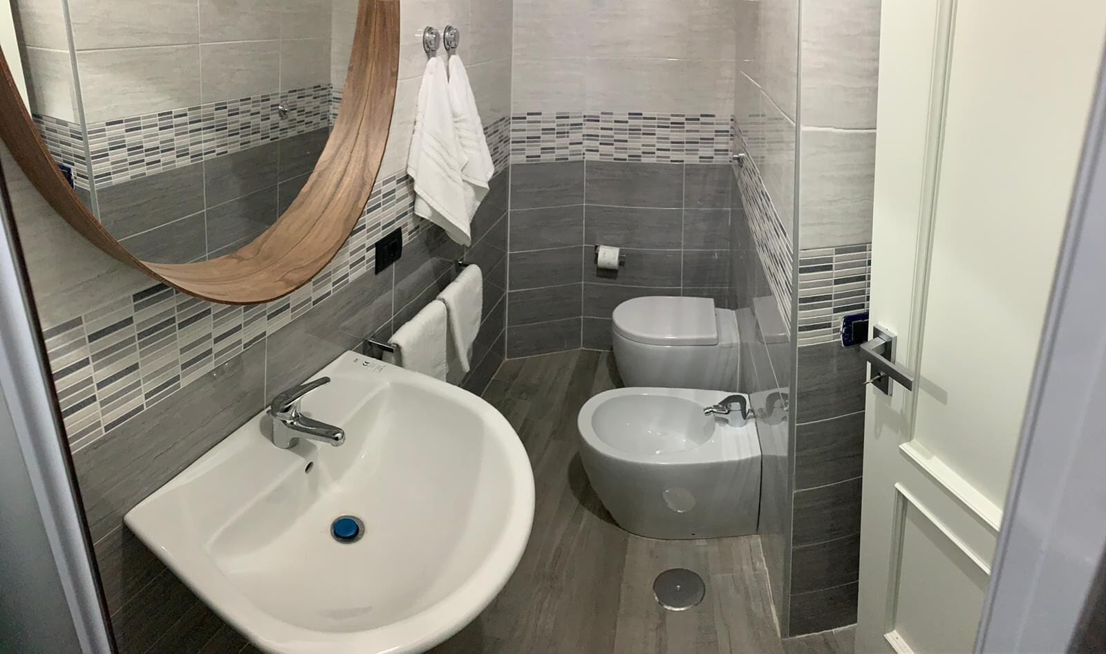 Et moderne badeværelse med en stor vask, to toiletter og et spejl.