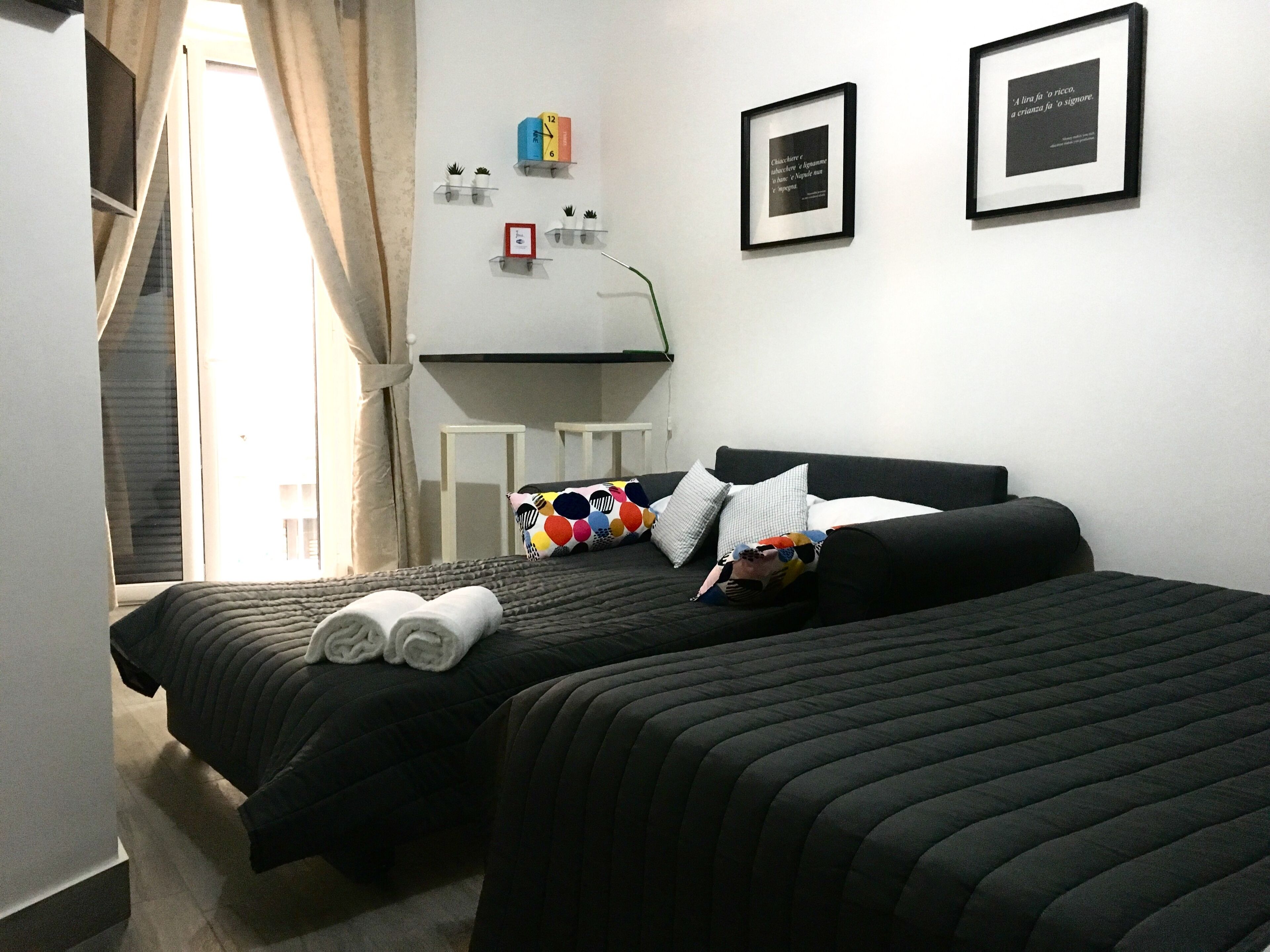 A hotel room with two beds, a desk, and a small window.