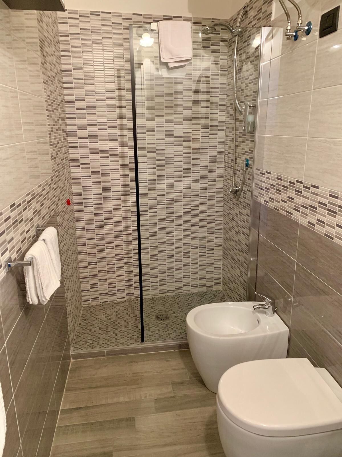 A modern bathroom with a glass-enclosed shower, a bidet, and a toilet.