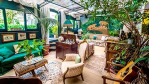 Una habitación acogedora y bien iluminada con un sofá verde, un sillón estampado y una guitarra de madera.
