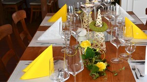 A dining table set with multiple wine glasses, yellow napkins, and a centerpiece with a green wreath and yellow roses. - Hotel Stadt Coblenz (Fachbach)