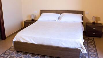 A neatly made bed with a wooden headboard, two bedside tables with lamps, and a patterned floor.